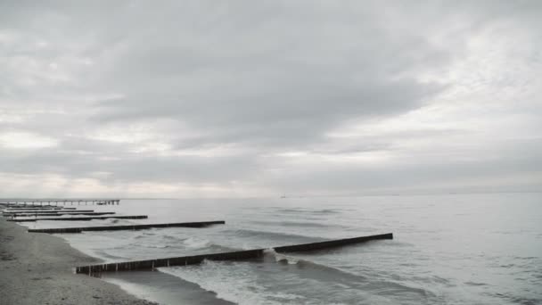 Ostsee, Wellen. die Seestadt mit der Seebrücke und dem Strand. Buhnen aus Holz — Stockvideo