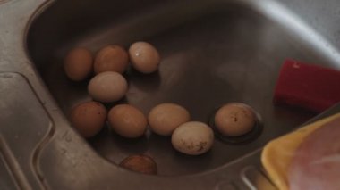 Yumurta mutfak lavaboda yıkanır, bir tencerenin içine su dökülür, yemek hazırlamak.