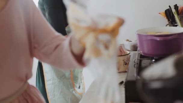 Zwei junge Frauen in Schürzen kochen in der Küche. sie stellen ein Geschirr auf den Gasherd, kochen einen Tintenfisch, aus nächster Nähe. — Stockvideo