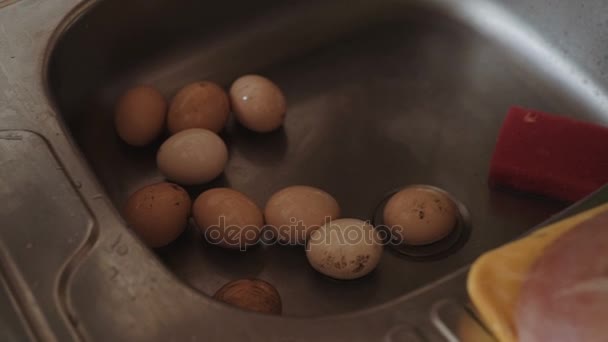 Ouăle se spală în chiuvetă în bucătărie, se toarnă apă într-o cratiță, se prepară alimente . — Videoclip de stoc