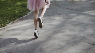 Genç ve güzel kadın pembe bir etek ve güneşli bir günde parkta bir smartphone giyen bir beyaz gömlek giyiyor. Üç eksenli Gimbal izleme atış stabilize