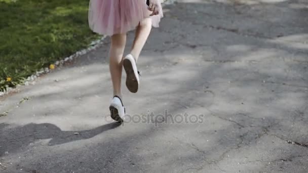 Jolie jeune femme en jupe rose et portant une chemise blanche portant un smartphone dans le parc par une journée ensoleillée. Plan de pistage stabilisé à trois axes Gimbal — Video