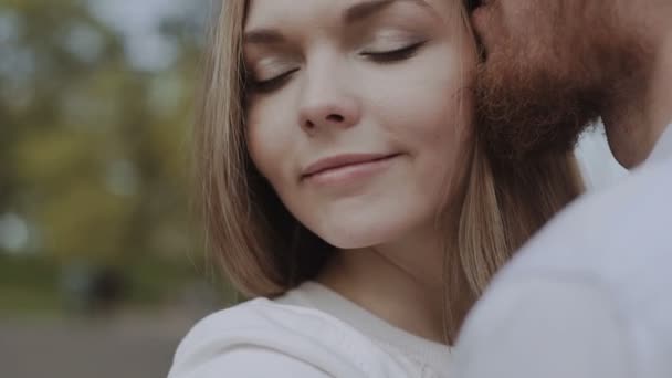 Nahaufnahme eines glücklichen Paares, das sich gerne küsst und umarmt, während es auf einer Straße der Stadt spaziert — Stockvideo
