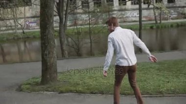 Kızıl saçlı genç adam sakallı longboard başlar yolculuk günbatımı Park ayak.