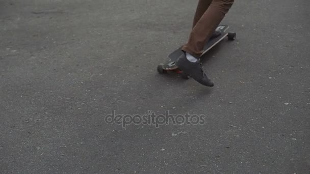 Jeune homme rousse avec un pied de barbe commence à monter sur longboard dans le parc du coucher du soleil. Gros plan — Video