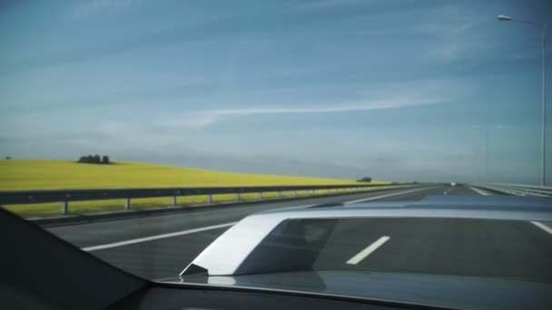 Воздушный кадр серого автомобиля, движущегося по дороге рядом с полем желтых цветов и фермы — стоковое видео