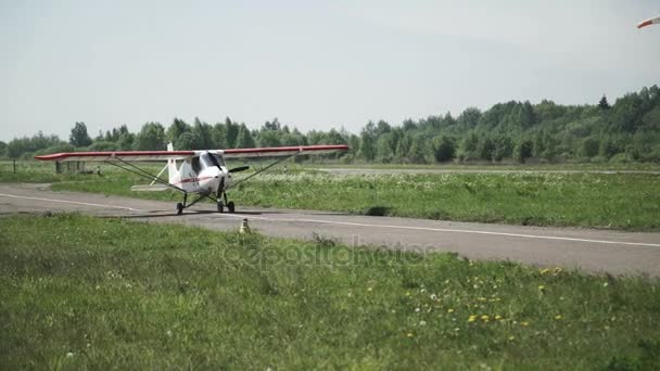 Un petit avion blanc se déplace sur la piste. L'hélice tourne. — Video