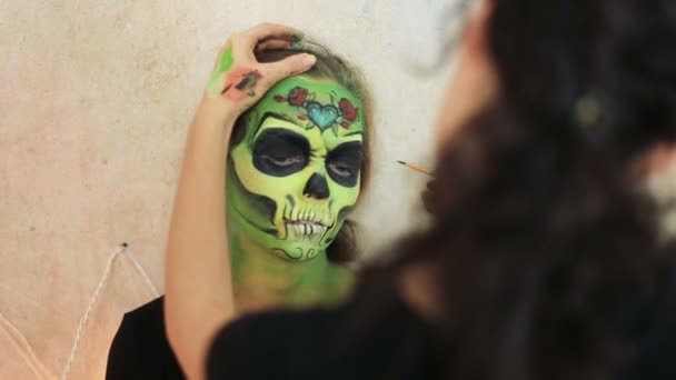 Mujer haciendo aquagrim arte de la cara en el maquillaje de Halloween con sus manos borlas verde esqueleto glamoroso miedo. Cráneo de azúcar princesa mexicana . — Vídeos de Stock