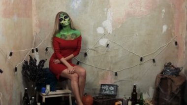 aquagrim yüz sanat halloween püsküllü üzerinde yeşil korkunç göz kamaştırıcı rhinestones iskelet. Meksikalı Prenses şeker kafatası. kadın model Kırmızı elbiseli kamera önünde poz.