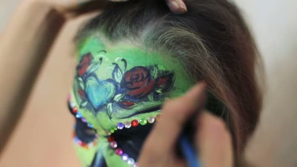 Mujer artista haciendo aquagrim arte de la cara en el maquillaje de Halloween con sus manos borlas verde espeluznante glamoroso esqueleto pedrería. Cráneo de azúcar princesa mexicana . — Vídeos de Stock