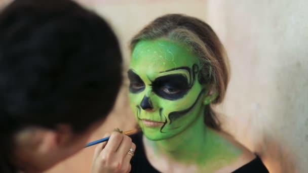 Mulher fazendo aquagrim rosto arte em halloween make-up com as mãos borlas verde esqueleto glamouroso assustador. Caveira de açúcar princesa mexicana . — Vídeo de Stock