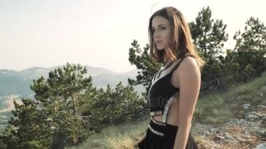 güzel genç kadın modeli bir dağ manzarası arka planda kamera poz siyah kabarık zarif uzun elbise.