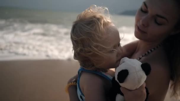 Jovem mãe abraços pouco encaracolado menina na praia do mar no verão — Vídeo de Stock