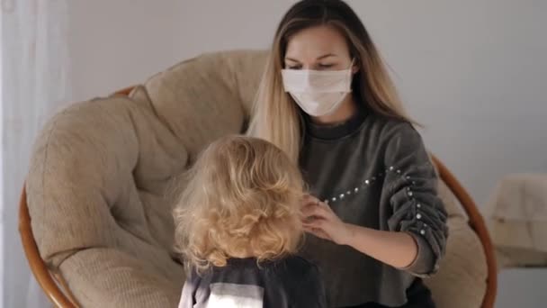 Jung mutter im ein medical mask puts ein mask auf sie tochter, aber die mädchen takes ab — Stockvideo