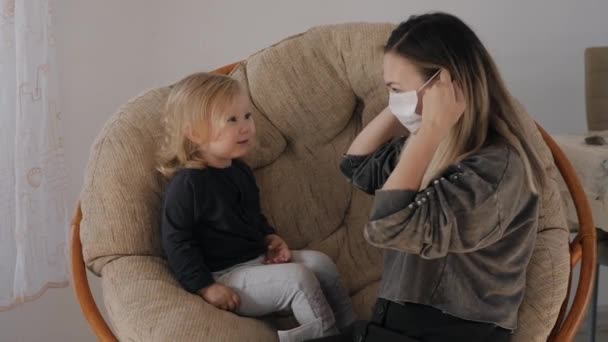 Giovane madre in una maschera medica mette una maschera su sua figlia, ma la ragazza decolla — Video Stock