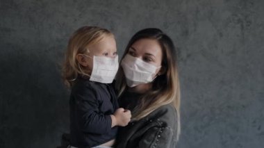Küçük kızı olan genç bir kadın koruyucu tıbbi maskeler taktı.