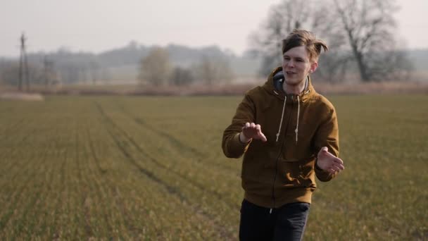 Joven deportista corre en el campo y lanza un bumerán al cielo — Vídeo de stock