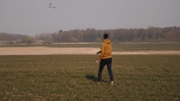 Ung idrottsman springer i fält och lanserar en bumerang i skyn — Stockvideo