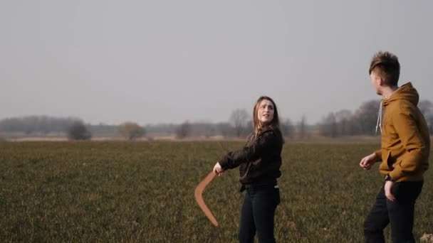 Jong paar verliefd samen lanceren een boemerang in een veld — Stockvideo