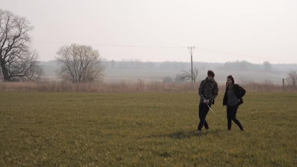 Joven pareja enamorada juntos lanzar un bumerán en un campo — Vídeo de stock