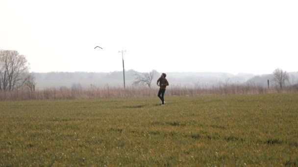 Joven deportista corre en el campo y lanza un bumerán al cielo — Vídeos de Stock