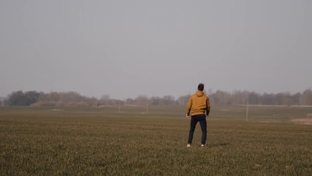 Joven deportista corre en el campo y lanza un bumerán al cielo — Vídeo de stock