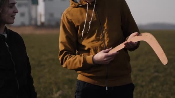Unga par förälskade tillsammans lansera en bumerang i ett fält — Stockvideo