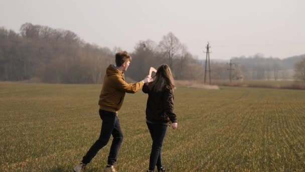 Jeune couple amoureux ensemble lancer un boomerang dans un champ — Video