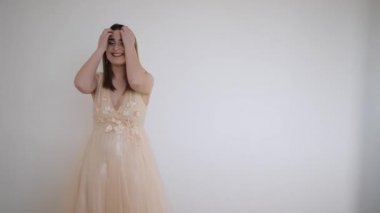 Duvar arkasında bej bir gelinlik giymiş güzel genç bir kadın.
