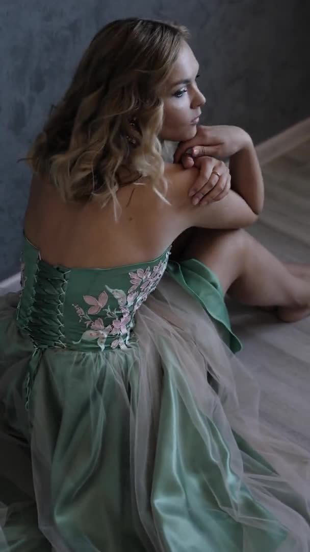 Young woman in evening dress posing sitting on grey wall closeup portrait — Stock Video