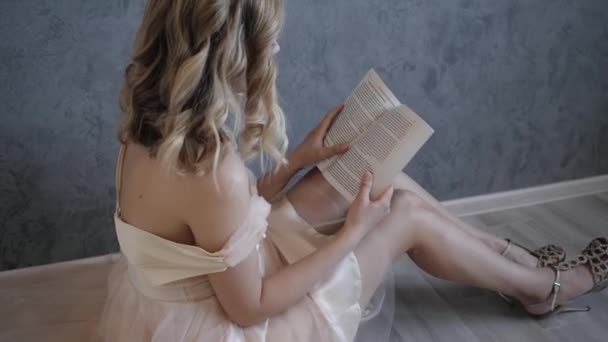 穿着米色婚纱的年轻漂亮的新娘在看书 — 图库视频影像