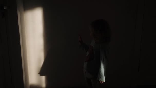 Маленькая девочка играет с тенью и солнечным светом — стоковое видео