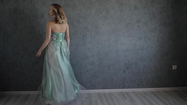 Vacker kvinna i aftonklänning poserar sitter på en grå vägg närbild porträtt — Stockvideo