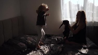 Mutlu anne ve küçük tatlı kızı evdeki yatakta zıplıyorlar.