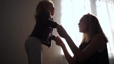 Mutlu anne ve küçük kızı birlikte evdeki yatakta zıplıyorlar.