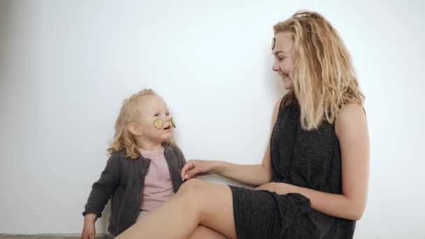 Young mother and little daughter white mask with cucumbers on her face — Stock Video