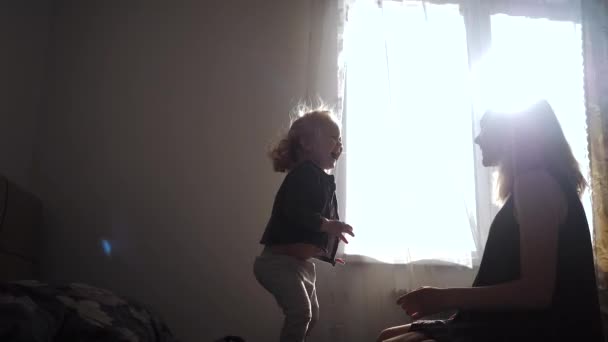 Lycklig mor och liten dotter tillsammans hoppar på sängen hemma — Stockvideo