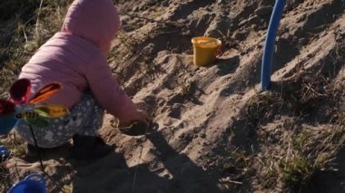 Küçük kız kum havuzunda oynuyor.