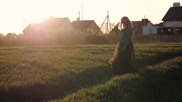 Mujer joven en un vestido largo negro y chaqueta de cuero corriendo por el campo — Vídeo de stock