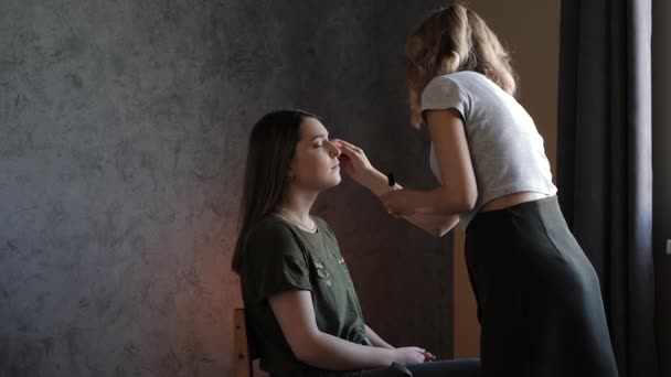 Jovem maquilhadora fazendo maquiagem para a noiva — Vídeo de Stock