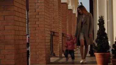 Anne ve kızı el ele yürüyorlar.