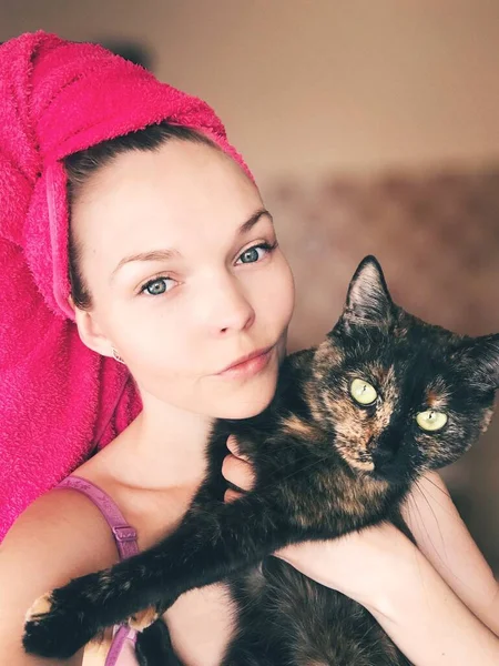 Porträt einer jungen Frau in einem leuchtend rosa Handtuch mit einer Katze — Stockfoto