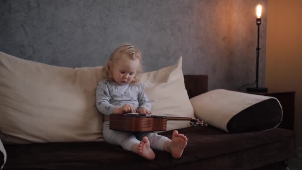 Una niña aprende a tocar un ukelele instrumento musical — Vídeo de stock