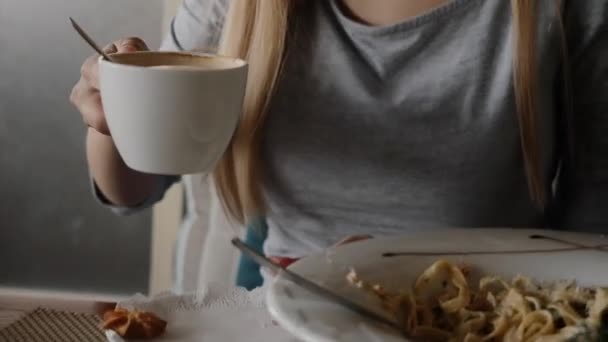 커피 잔을 들고 카페에서 점심을 먹고 있는 젊은 여성 — 비디오