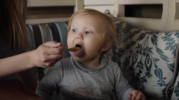 Мати годує маленьку дівчинку розтертою ложкою крупним планом — стокове відео