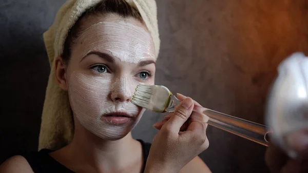 Een jonge vrouw krijgt crème schoonheid wit masker van zure room op het gezicht closeup Rechtenvrije Stockafbeeldingen