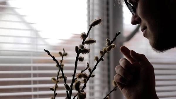 Jeune homme à lunettes renifler une plante d'intérieur — Photo