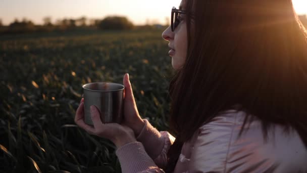 Mujer joven con gafas disfrutar de beber té caliente de la copa de hierro al aire libre — Vídeos de Stock