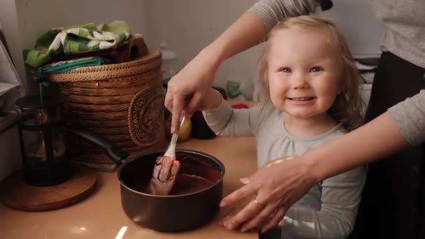 Malá holčička pomáhá její matce míchat těsto detailní portrét — Stock video