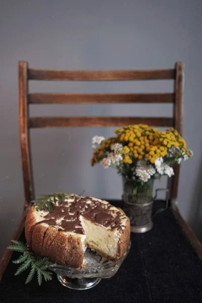 Cheesecake et fleurs sauvages sur la chaise noire — Photo